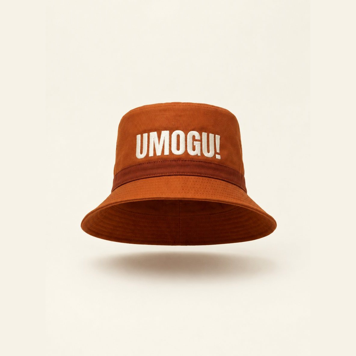 Burnt orange bucket hat embroidered UMOGU! in ivory.