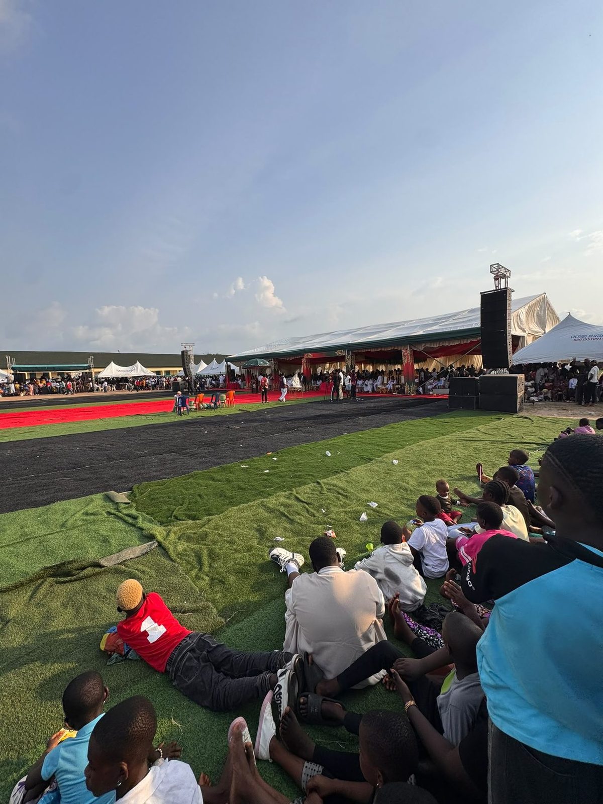The crowd on the turf watching the arena under a wide sky.