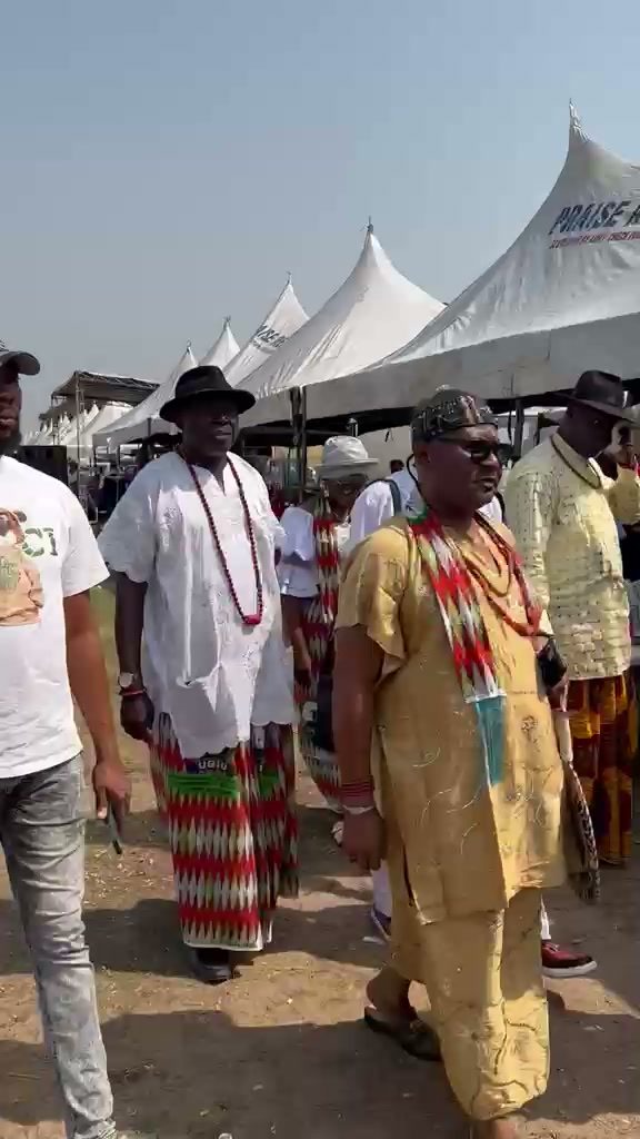 Chiefs in white and gold walking together between the tents.